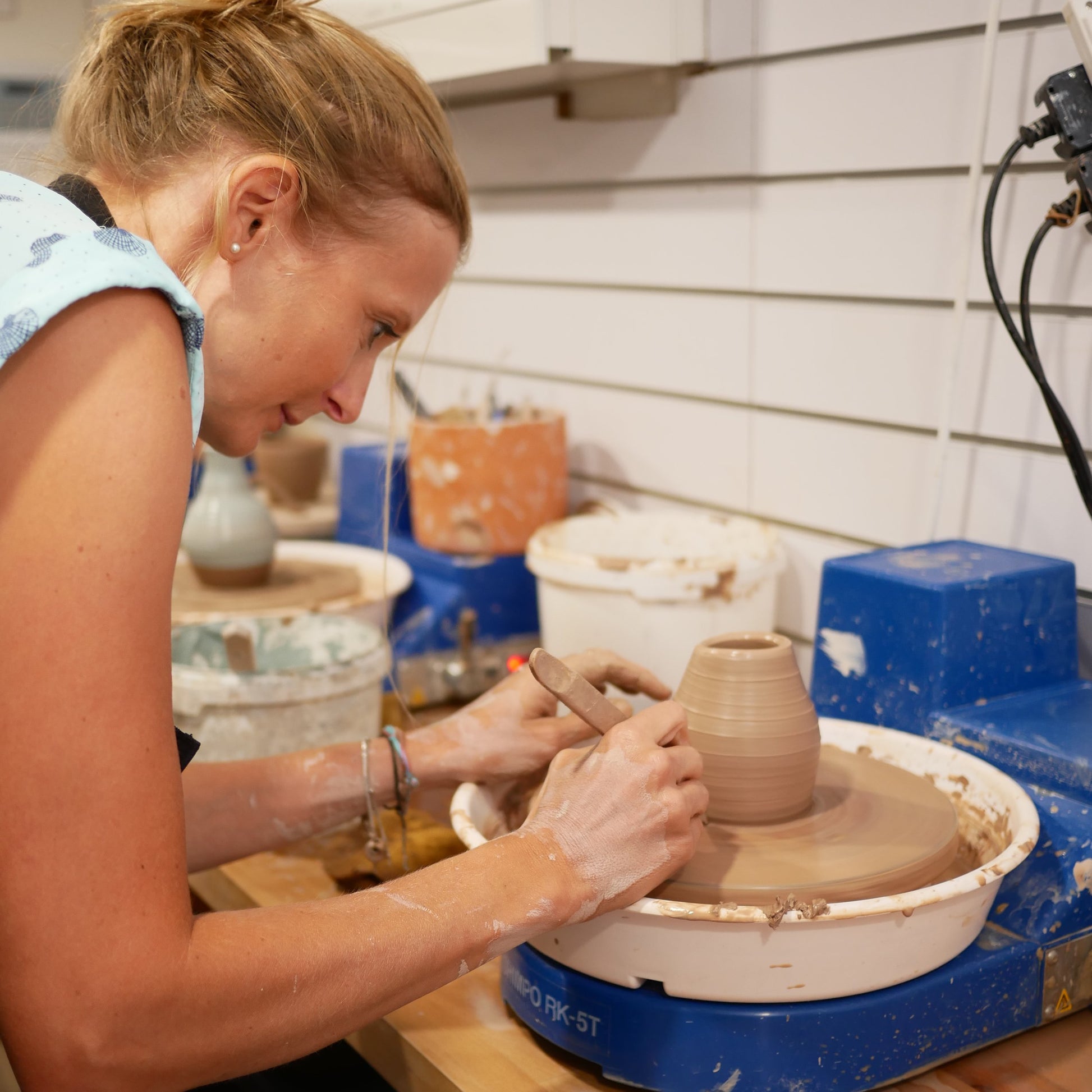 A person throwing a pot on the pottery wheel in one of our pottery workshops